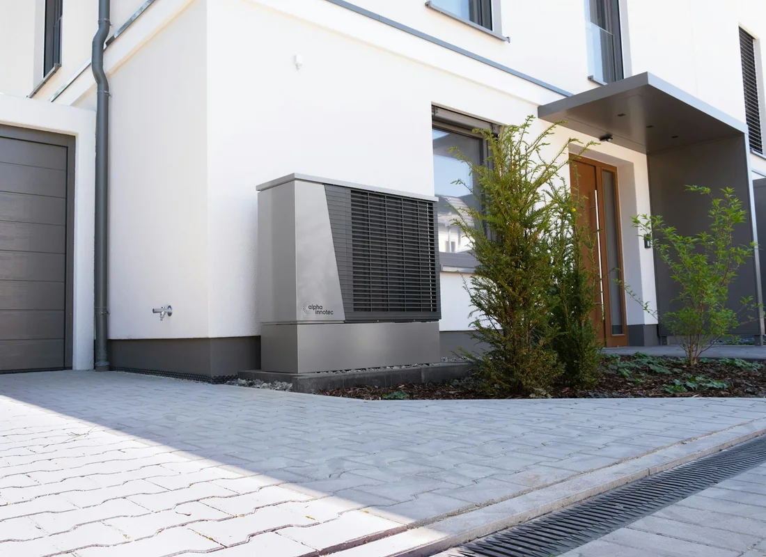 Photographie d’une unité extérieure de pompe à chaleur installée le long d’une maison