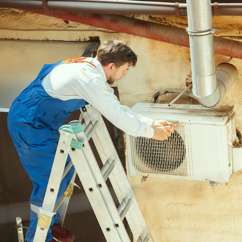 HVAC technician working on a capacitor part for condensing unit